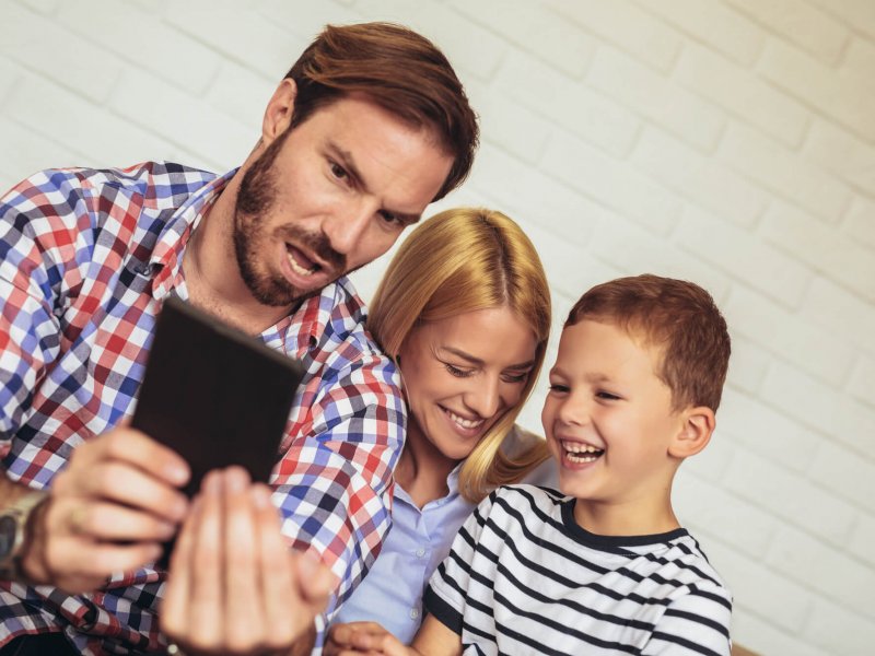 Happy family using digital tablet taking selfie at home, and having fun.